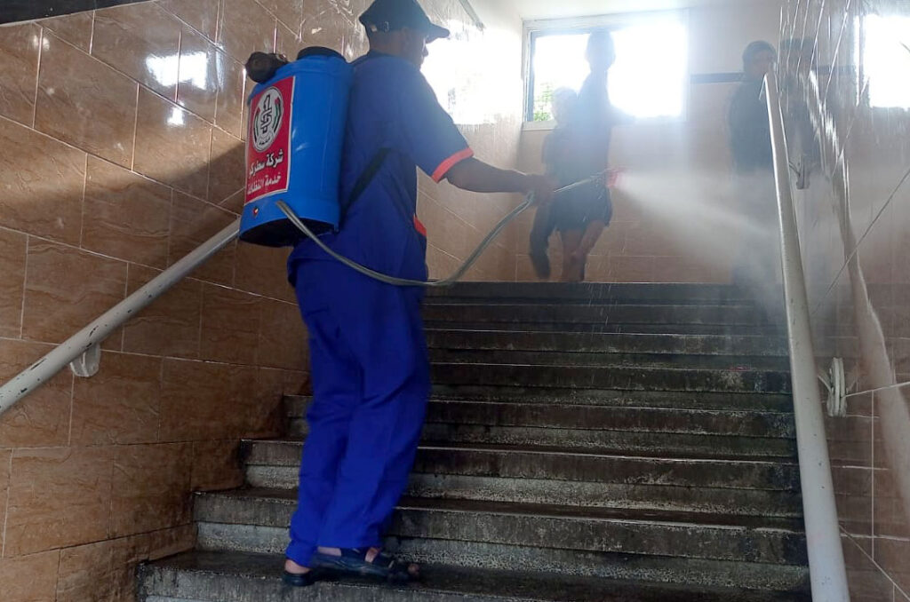 A man sprays cleaning fluid in a school stairwell.