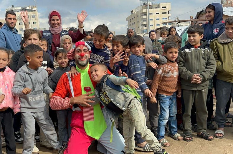 smiling child and clown in front of a happy crowd