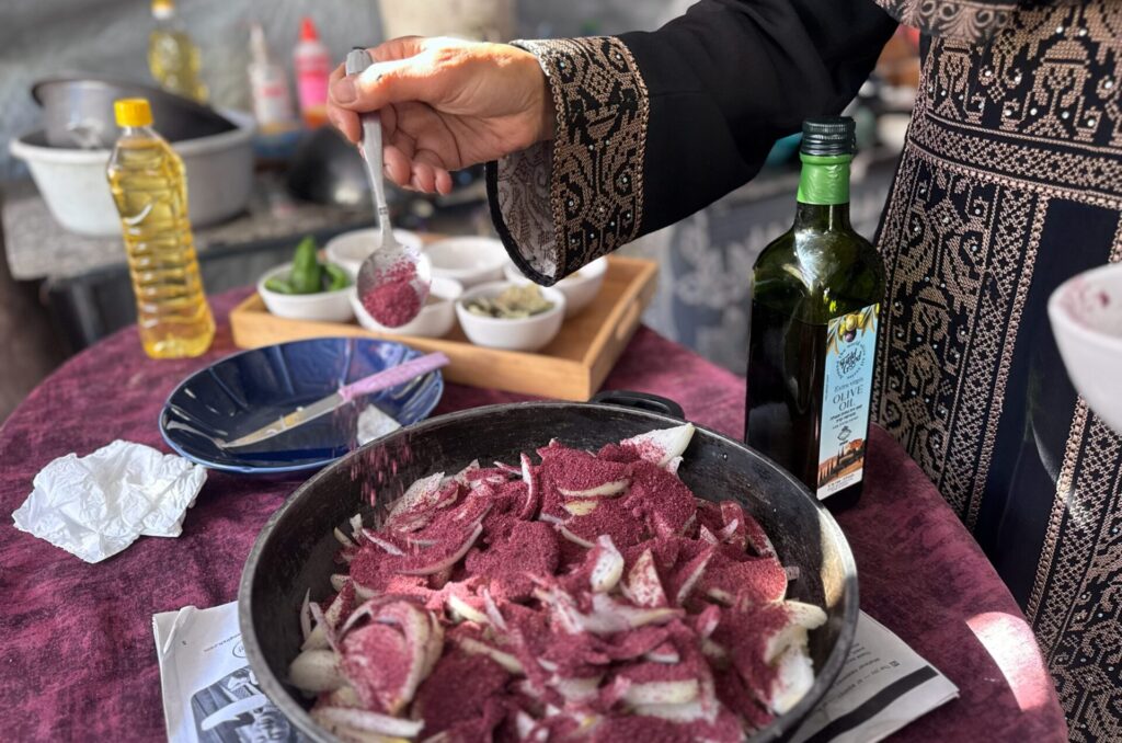 Um Zaki sprinkling sumac and olive oil on chopped onions