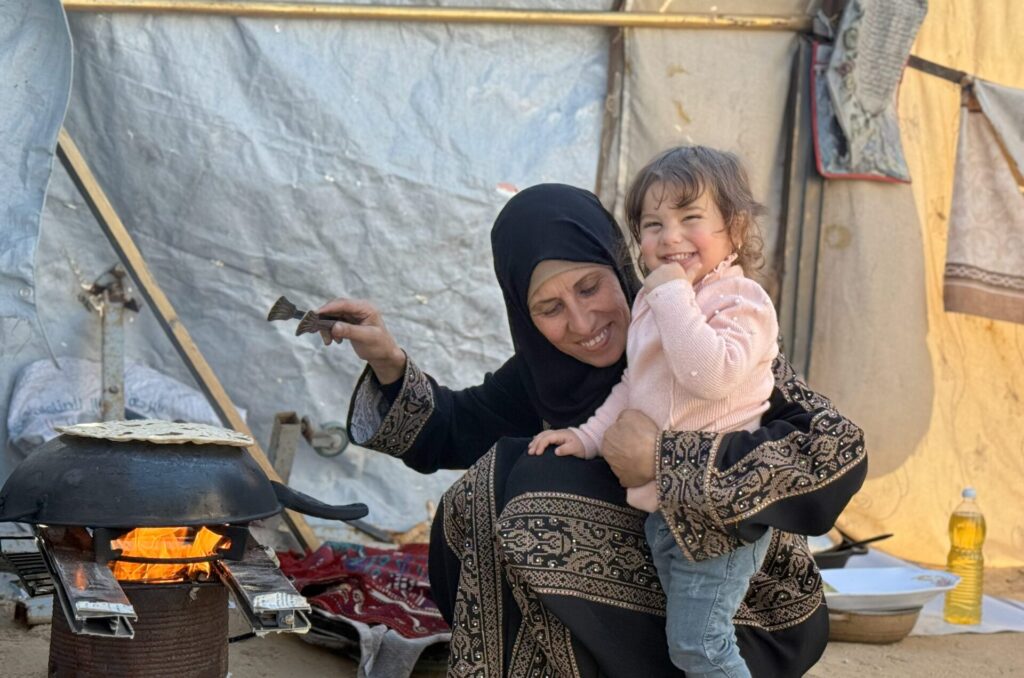 Um Zaki laughing with her young grandaughter and cooking farasheeh bread