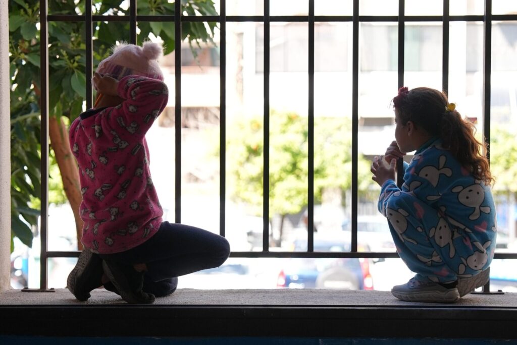 two young girls looking out a window