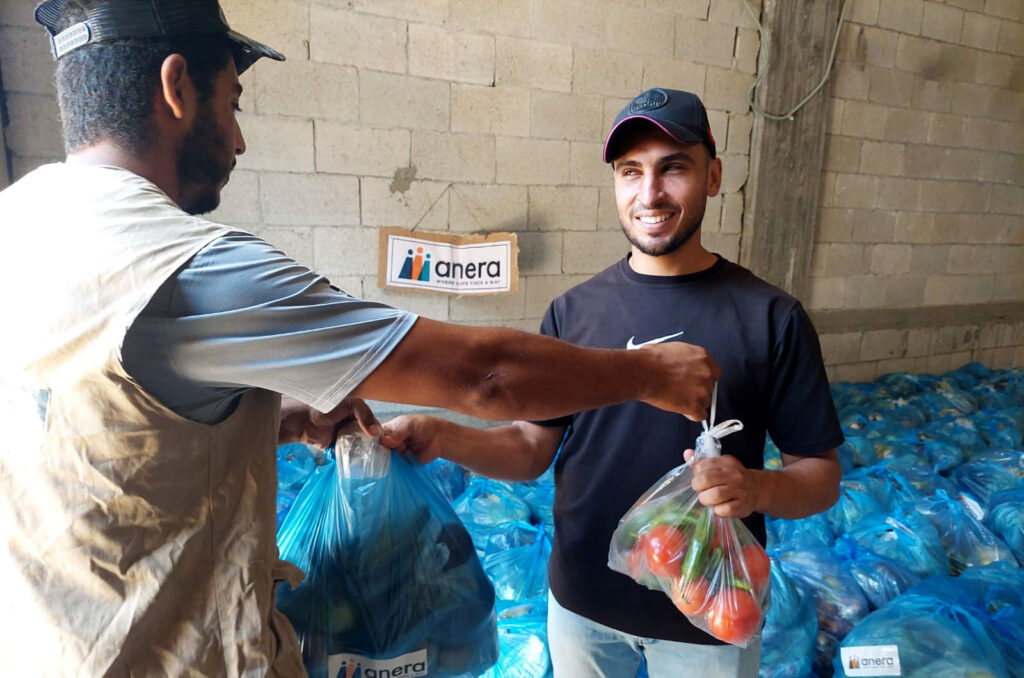 Anera team member handing a bag of vegetables to a community member in Gaza on July 12, 2026.
