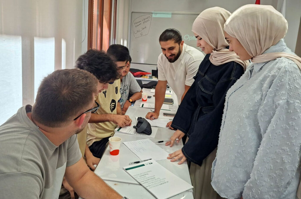 Students gather together in a classroom with notes and coffees.