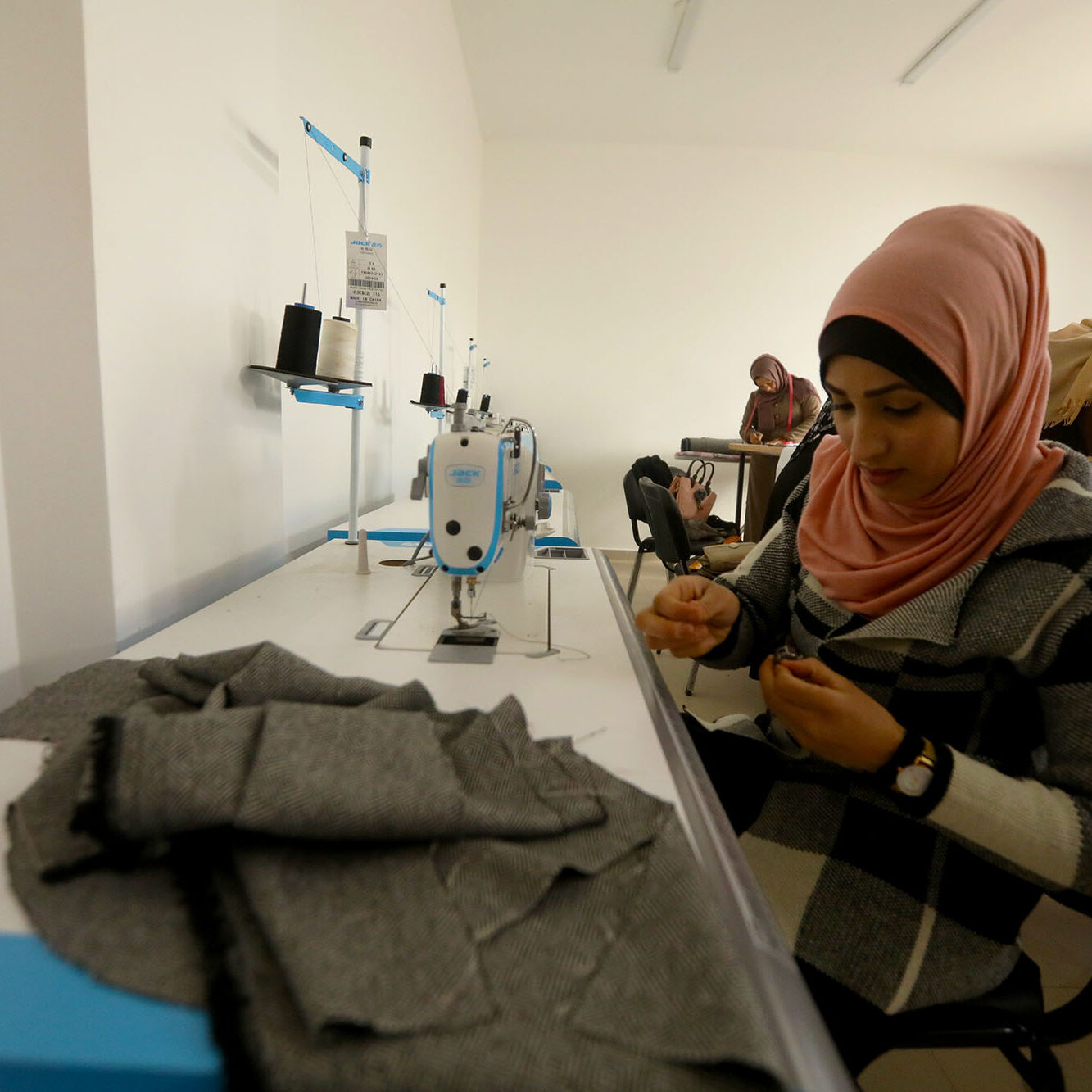 A Palestinian woman readies a spool of thread to add to her sewing machine as part of an Anera sewing training course at the CSSL center in Beit Hanoun, Gaza.