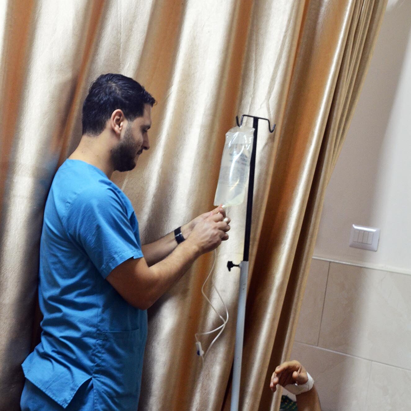 A nurse dilutes an antibiotic in the saline bag for a patient at Al Quds Hospital.