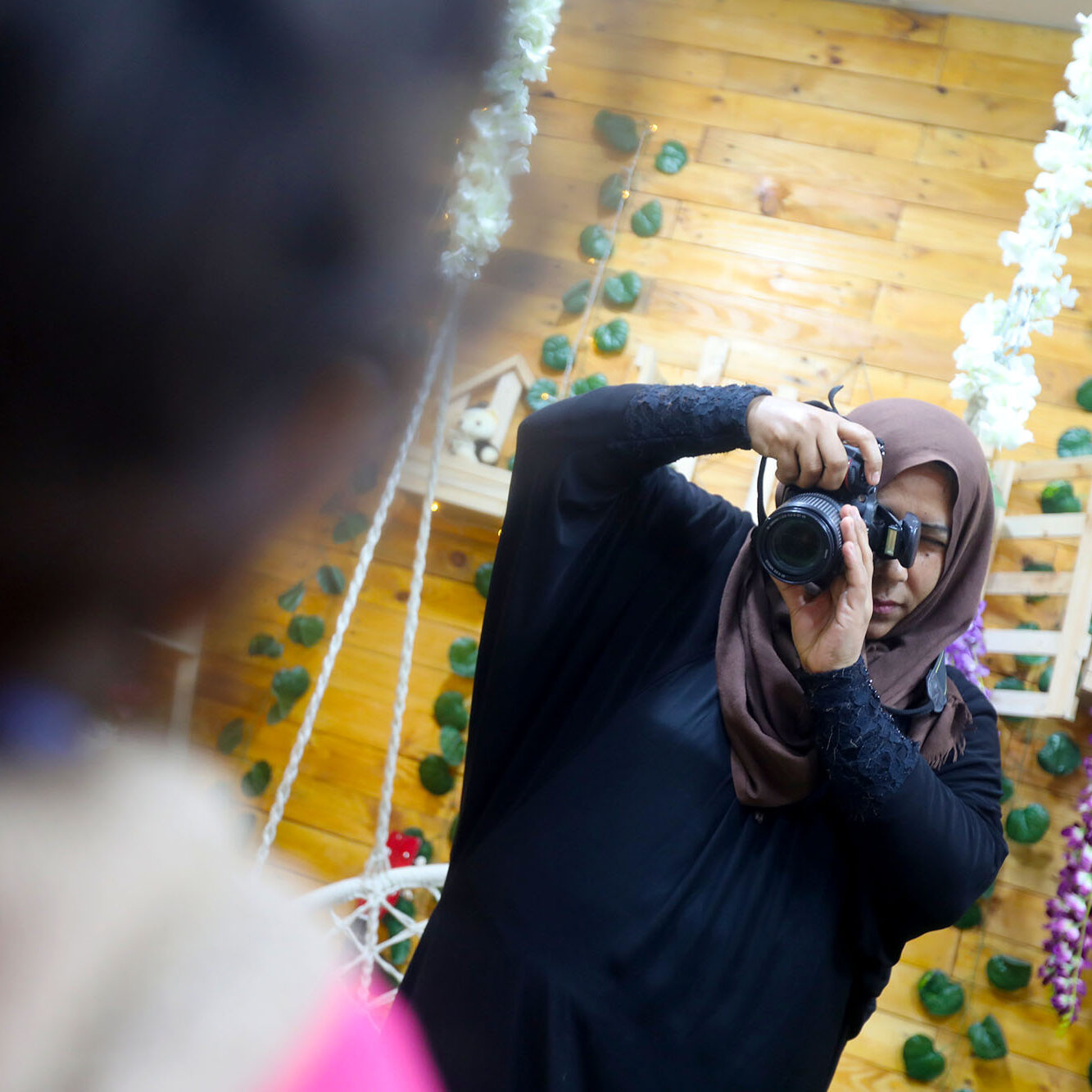 Nisreen takes the photo of a young customer inside a studio at the CSSL center in Beit Hanoun, Gaza. She is learning photography through one of Anera's training courses.