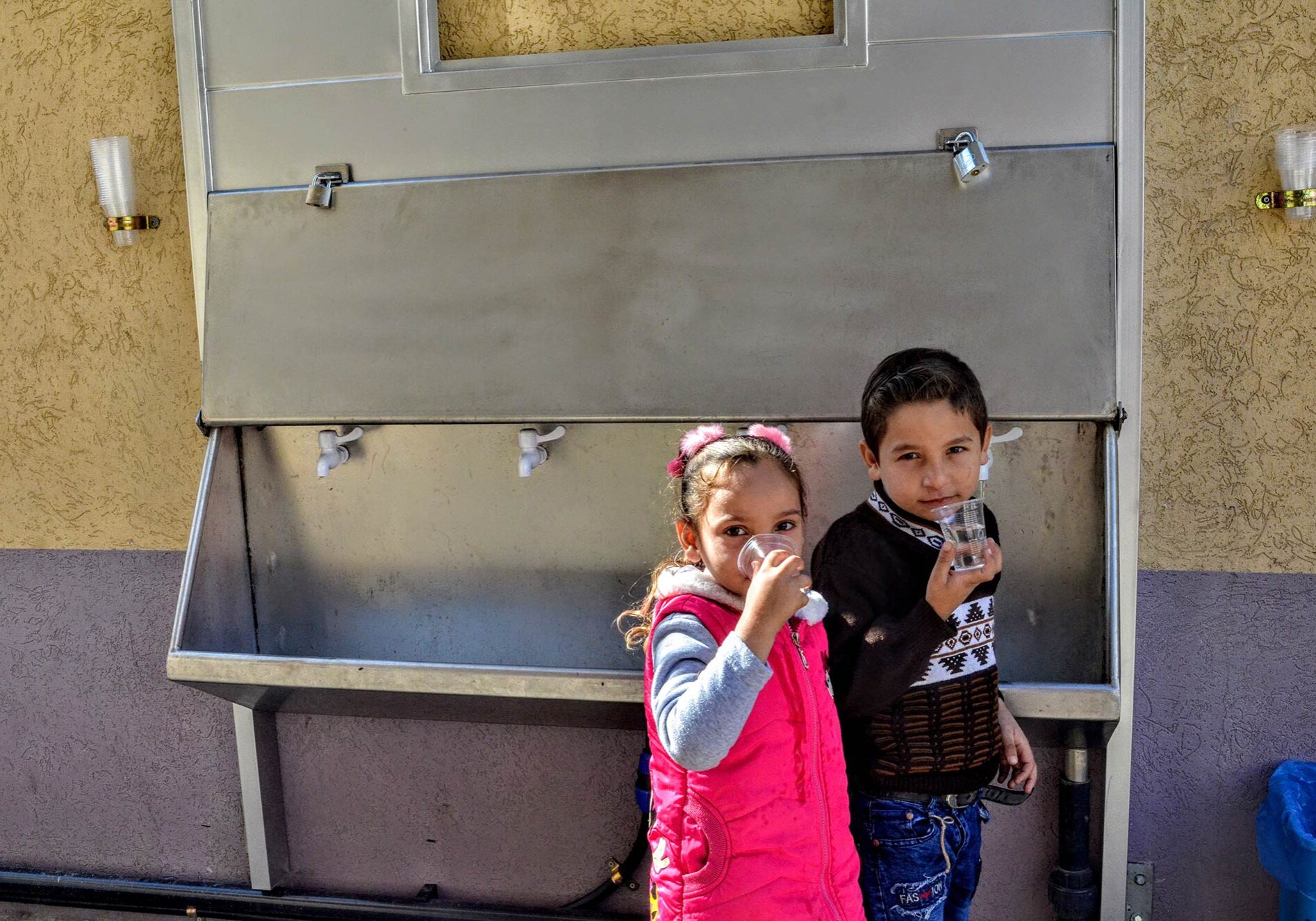 Children drink clean water supplied by a desalination unit at a water fountain at Ard El Insan clinic in Gaza.